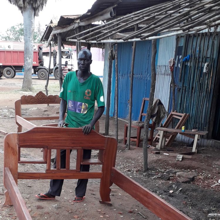 A South Sudanese man building bed frames to sell